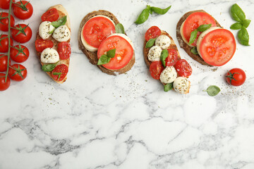Delicious sandwiches with mozzarella, fresh tomatoes and basil on white marble table, flat lay. Space for text