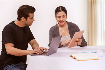 Couple working from home using laptop and digital tablet