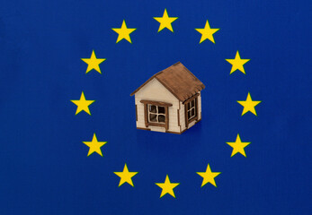Small wooden house on the background of the flag of the European Union (EU).