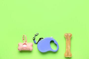 Pet waste bags, leash and chew bone on green background