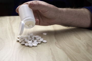 a man pours pills out of a plastic bottle on the table