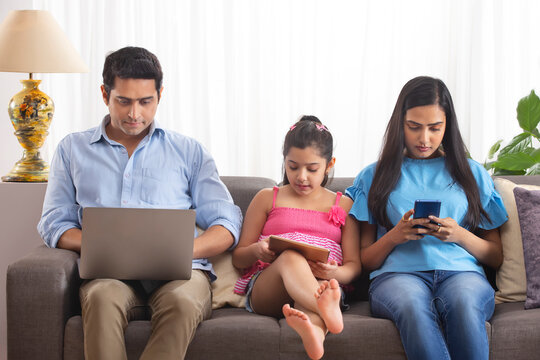 Family members using gadgets in living room 