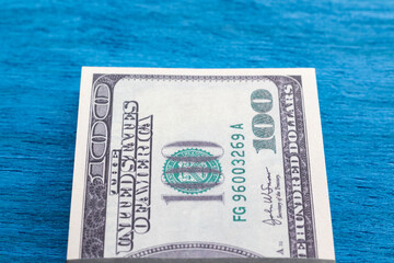 A wad of dollars lying on a blue table. American paper currency.