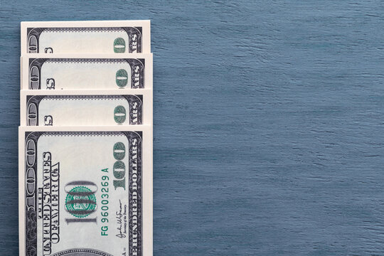 Packs of American hundred-dollar bills lie on a blue gray wooden background and copy space.