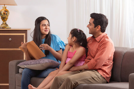 Family Members Talking With Each Other While Sitting On Sofa At Home