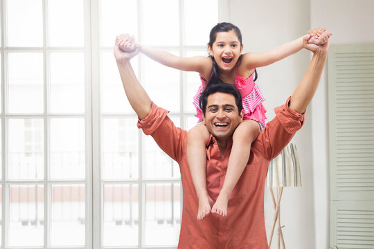 Father carrying daughter on his shoulder in living room