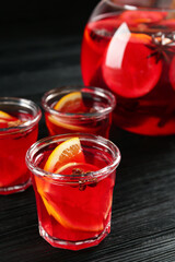 Bowl and glasses of delicious aromatic punch drink on black wooden table