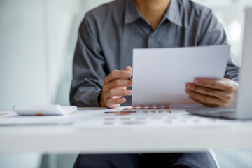 Fototapeta premium Business man hands hold documents with financial statistic stock photo,discussion and analysis data the charts and graphs,Financial business man calculating corporate income tax data Finance concept.