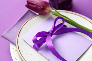 Simple table setting with flower on purple background, closeup
