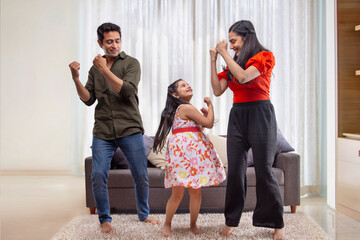 Parent and daughter dancing  together in living room