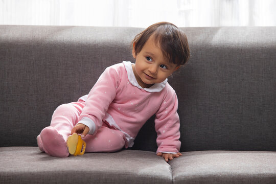 Portrait of a cute baby sitting on sofa and looking elsewhere