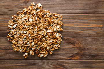 Walnut grains are scattered on a wooden background.