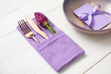 Simple table setting with flower on light wooden background, closeup