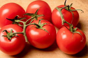 Ripe red organic juicy tomatoes on a vine on an old wooden board