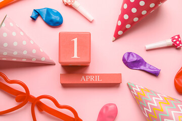 Calendar with date of April Fools Day and party decor on pink background