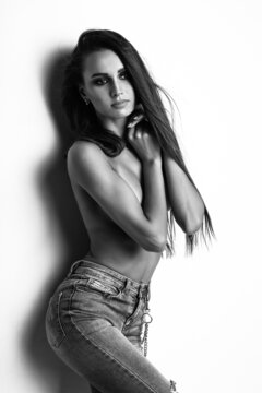 Black and white studio photo of a Girl model with long hair dressed in light jeans. Fitness body.