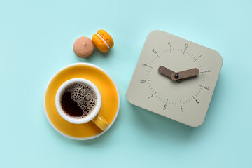 New alarm clock with cup of coffee and macaroons on blue background