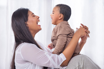 Portrait of happy mother playing with her little baby at home