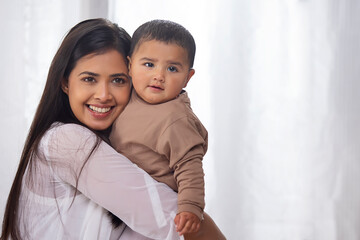 Portrait of happy mother hugging her little baby at home