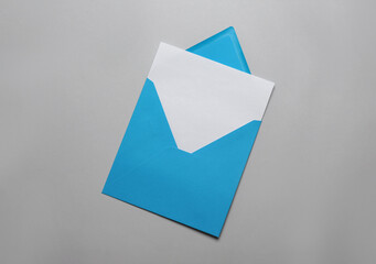 Light blue envelope with blank letter on grey background, top view