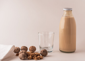 glass bottle with milk, walnuts and a glass on the table.