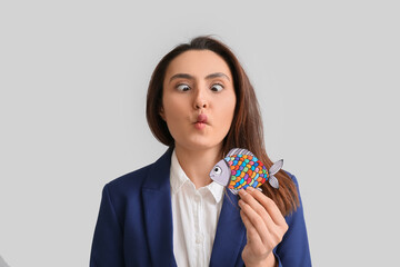 Funny young woman with paper fish on grey background. April fools day celebration
