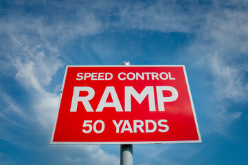 Street sign, speed control ramp sign. Red against a blue sky.
