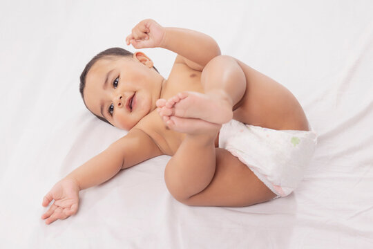 Cute baby in diaper lying on bed