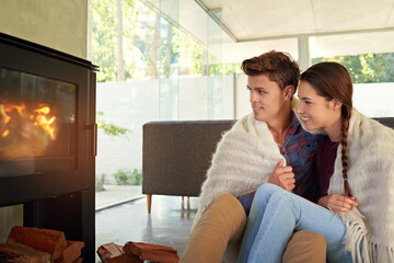 Cuddling by the fireplace. Shot of an affectionate couple sitting by the fireplace in their living room.