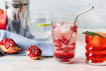 Glasses of tasty pomegranate cocktail on light background