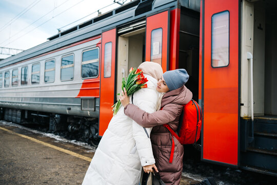 girls say goodbye hugging on the station platform