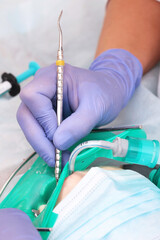 Modern dental clinic. Treatment of caries in a child. General anesthesia. Breathing tube. Macro photography. The concept of healthcare. Vertical photo.Unrecognizable persons.