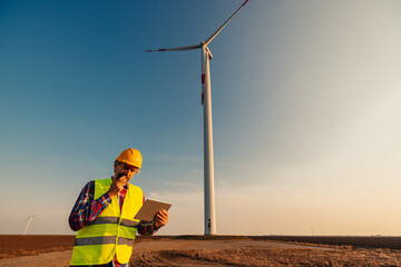 Engineer checking wind turbines at field and using technology