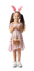 Cute little girl with bunny ears and Easter eggs in basket on white background