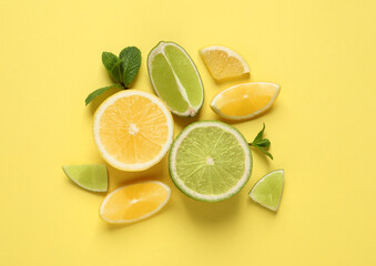 Fresh ripe lemons, limes and mint leaves on yellow background, flat lay