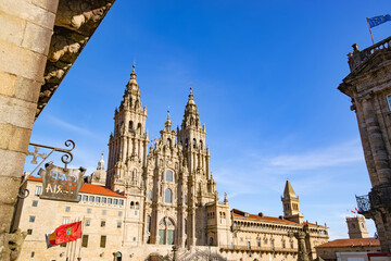 Fototapeta na wymiar Cathedral of Santiago de Compostela facade with institutional flags in Obradoiro square and blue sky