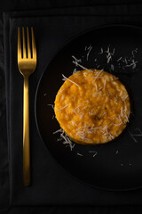 Milanese risotto on a black plate.