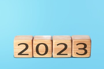 Flipping wooden cubes 2022 to 2023 with blue background. Happy new year 2023.