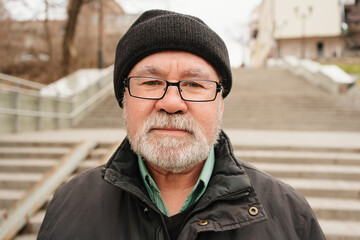 an elderly man with a gray-haired beard and wearing a hat with glasses. age-related vision...