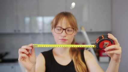 Woman try to figure out how to use a measure tape. Woman with little experience in carpentry - Powered by Adobe