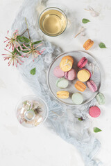 Fototapeta na wymiar Colorful french macaroon cakes. Macaroons with jasmine flowers and tea on white table background. Selective focus