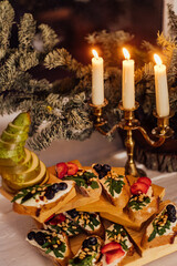 christmas dinner with candles. Italian bruschetta with cream cheese, strawberry, arugula and balsamic vinegar sauce with honey
