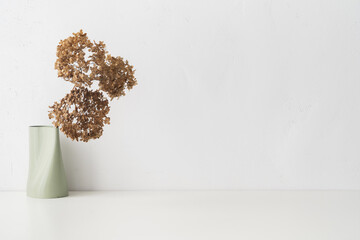 Table with dried flowers against white wall. 