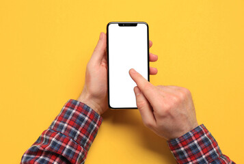Man using smartphone on yellow background, closeup