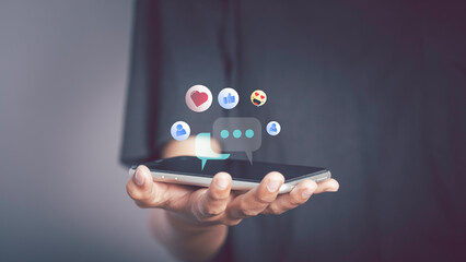 Live Chat on Communication social network Concept. Person hand using smartphone typing, playing social media chatting conversation in chat box icons pop up.