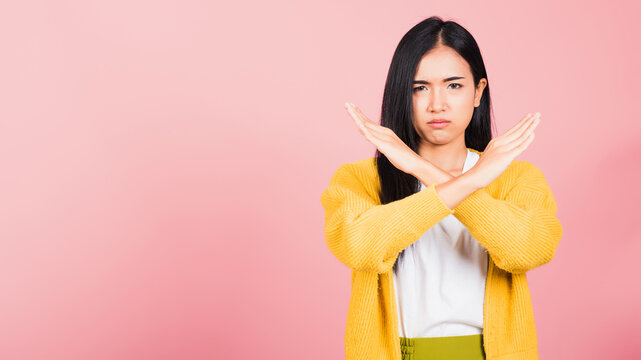 Portrait Asian Beautiful Young Woman Unhappy Or Confident Standing Wear Holding Two Cross Arms Say No X Sign, Studio Shot Isolated Pink Background, Thai Female Pose Reject Gesture With Copy Space