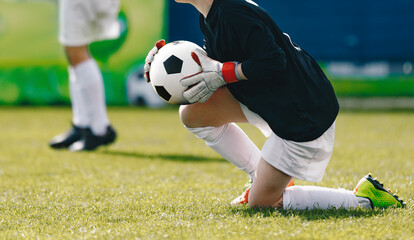 School boy as a soccer goalie catching football ball during a tournament game. Children playing sports outdoor. Goalie holding soccer ball