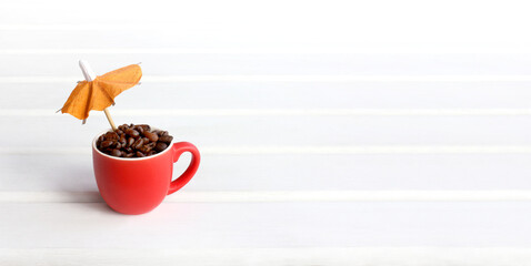 red cup with coffee beans and a small orange umbrella. summer soft roast