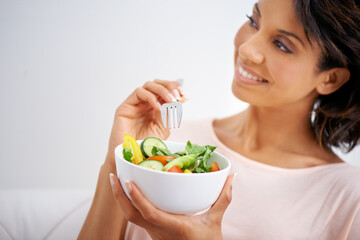 For a taste that inspires. Shot of a young woman enjoying a salad at home.