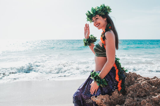 Hawaiian woman waves to the camera and smiles relaxed on a paradisiacal beach. Oriental and exotic beauty.